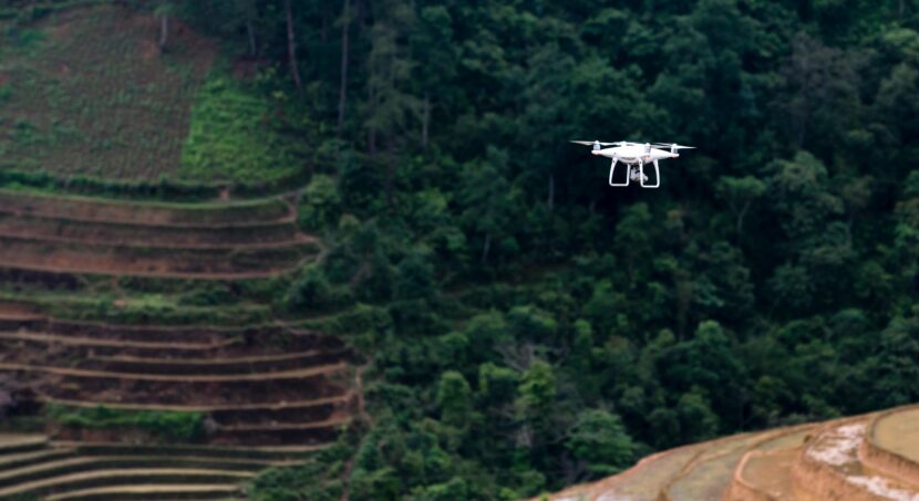 Cinematic drone capturing a traveler standing on a cliff at golden hour overlooking mountains and ocean, representing aerial storytelling and filmmaking