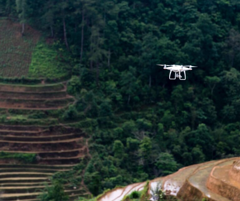 Cinematic drone capturing a traveler standing on a cliff at golden hour overlooking mountains and ocean, representing aerial storytelling and filmmaking