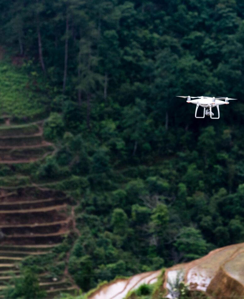 Cinematic drone capturing a traveler standing on a cliff at golden hour overlooking mountains and ocean, representing aerial storytelling and filmmaking