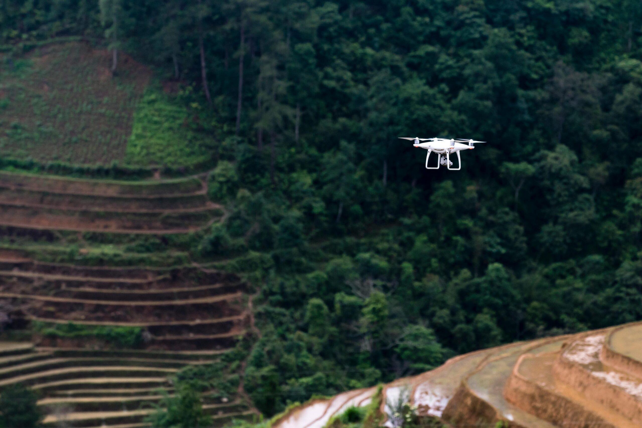 Cinematic drone capturing a traveler standing on a cliff at golden hour overlooking mountains and ocean, representing aerial storytelling and filmmaking