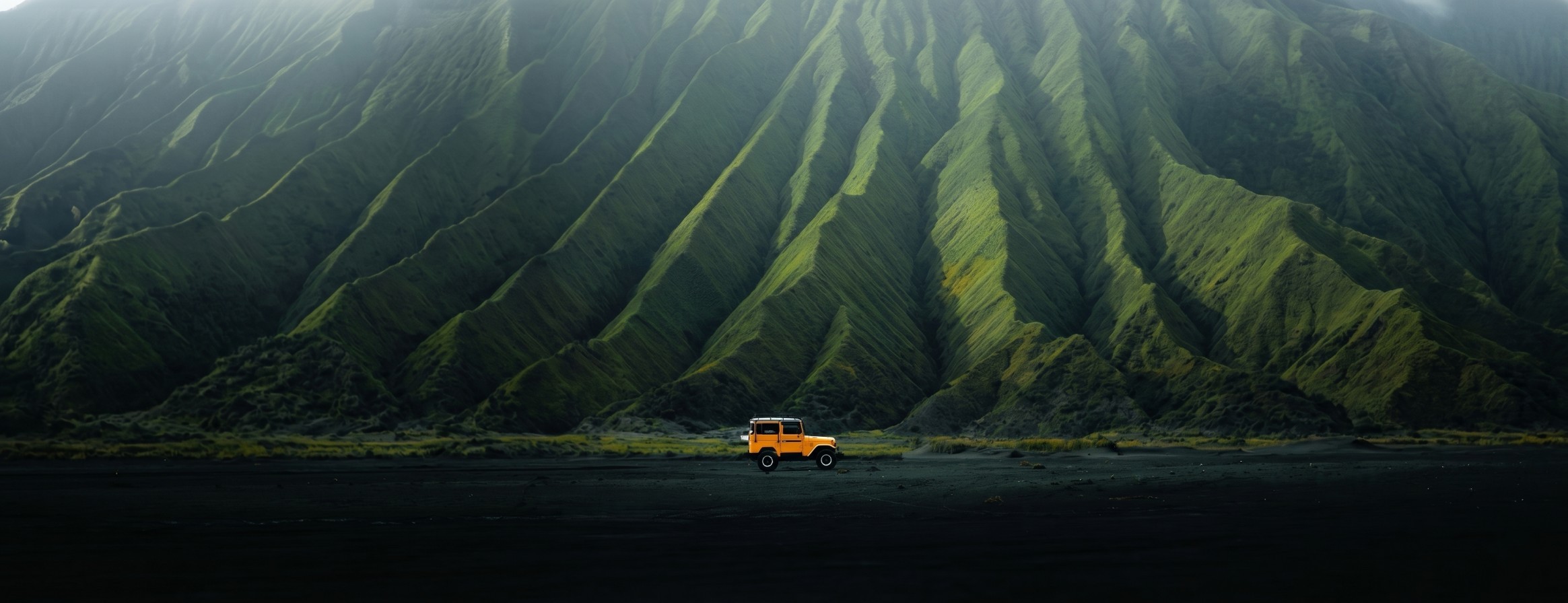 Yellow off-road vehicle parked in front of dramatic green mountains under soft morning light.